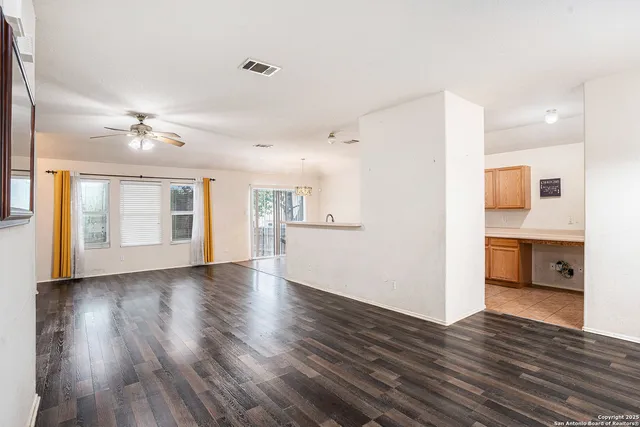 a view of an empty room with a window and wooden floor