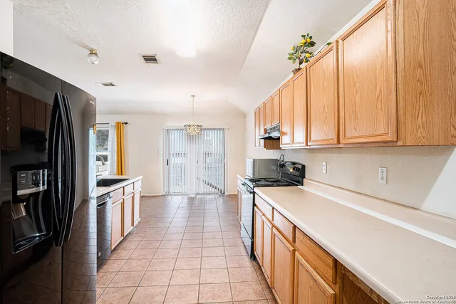 a kitchen with stainless steel appliances a stove top oven a sink a refrigerator and cabinets