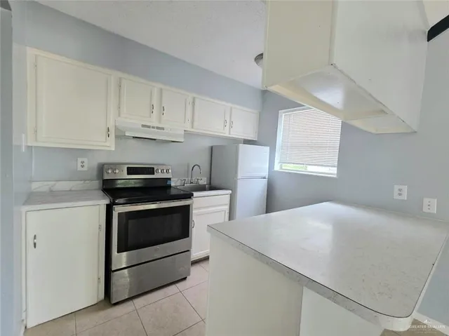 a kitchen with stainless steel appliances a sink dishwasher a stove and white cabinets