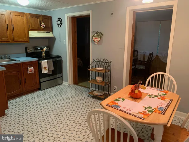 a kitchen with stainless steel appliances kitchen island granite countertop a refrigerator a stove a sink a dining table and chairs