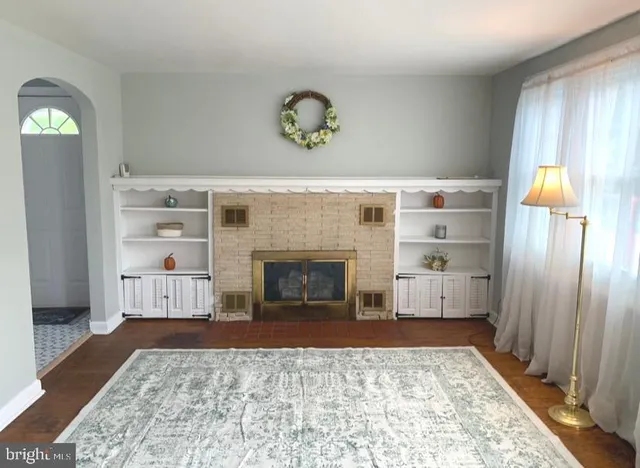 a living room with a fireplace furniture a rug and a window