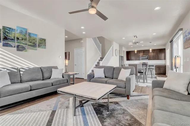 a living room with furniture kitchen view and a wooden floor