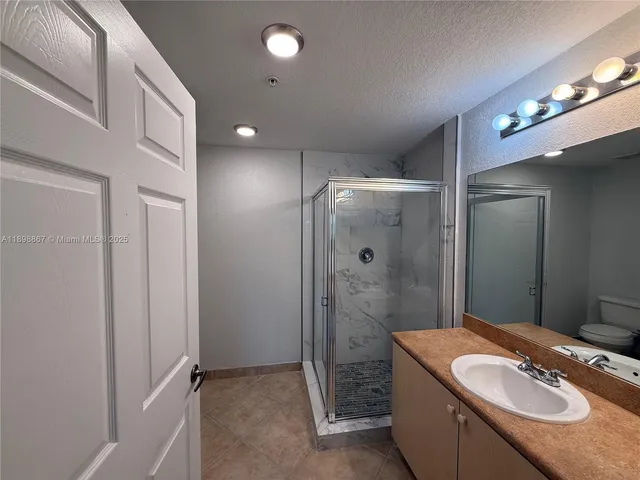 a bathroom with a granite countertop sink a mirror and a shower