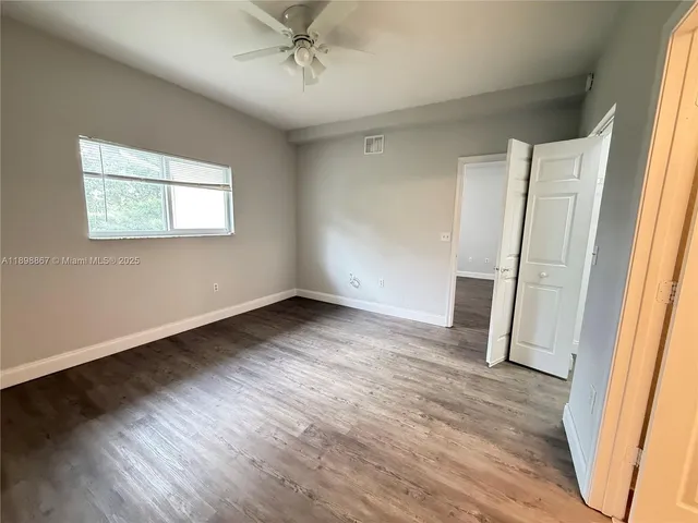 a view of empty room with wooden floor and fan