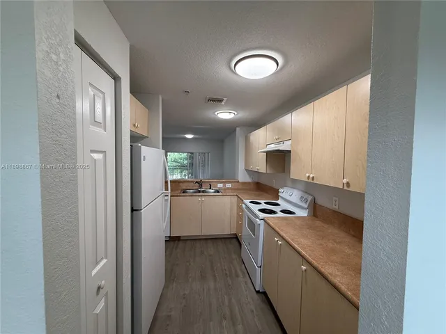 a kitchen with a refrigerator a sink and white cabinets