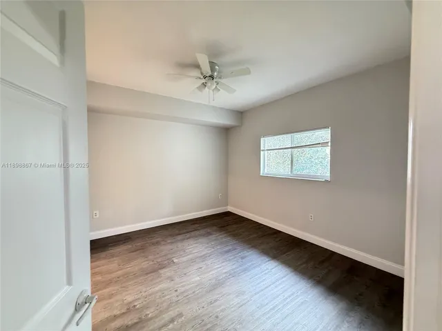 an empty room with wooden floor ceiling fan and windows