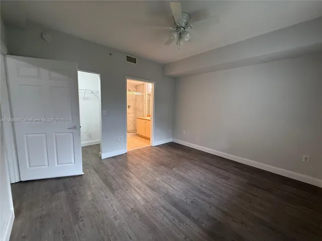 a view of empty room with wooden floor and fan
