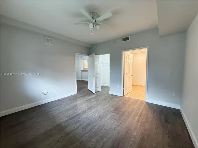 an empty room with wooden floor and a ceiling fan