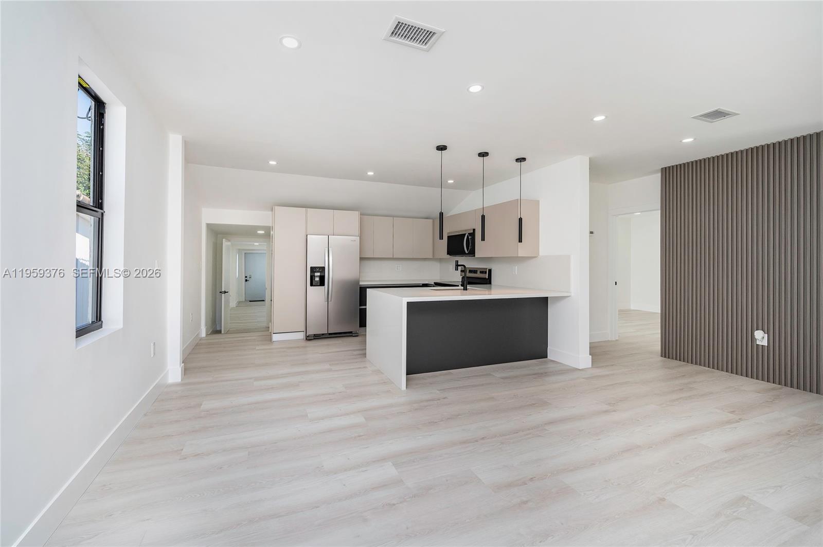 2363 Southwest 11th Terrace Miami, FL 33135 - Photo 15 of 49 a large white kitchen with kitchen island a sink stainless steel appliances and cabinets