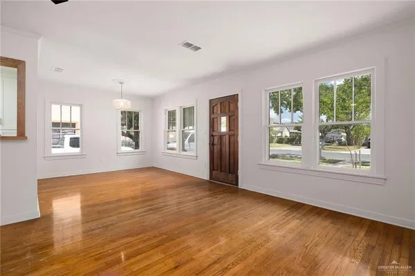 a view of an empty room with wooden floor and a window