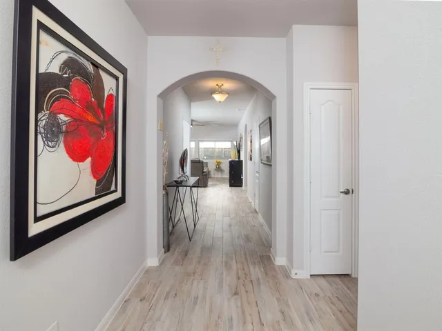 a view of a hallway with wooden floor and a painting on the wall
