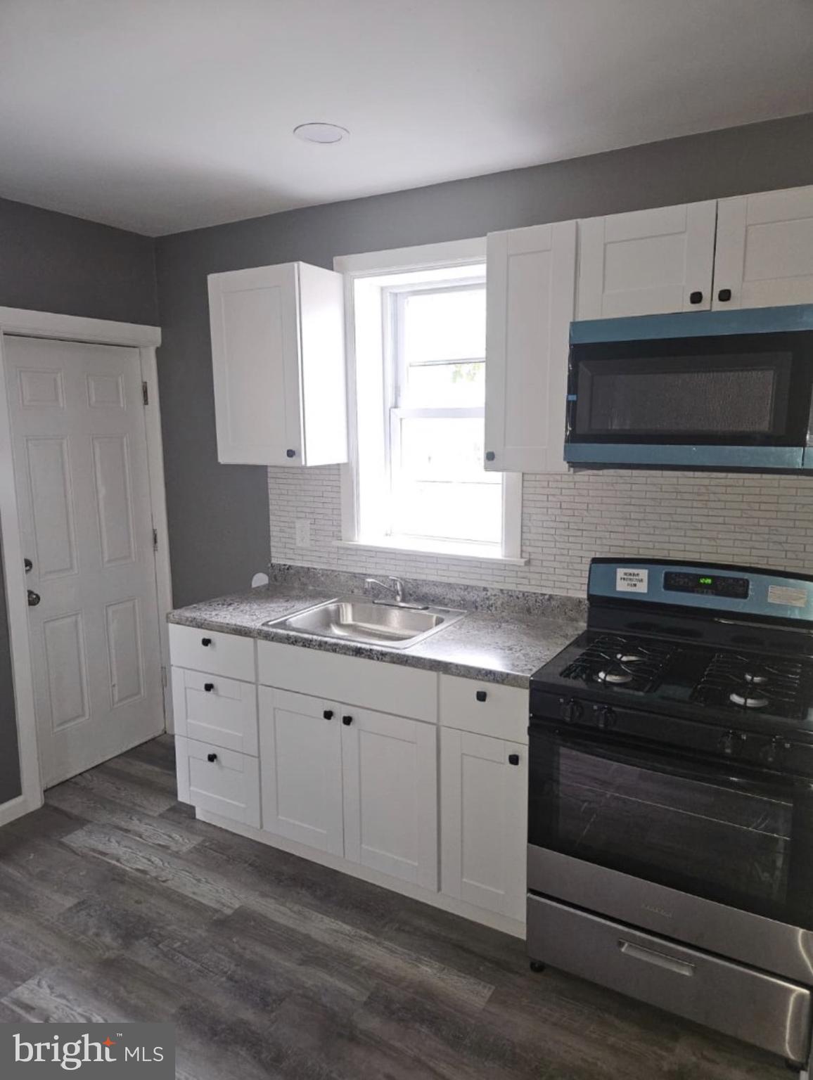 5554 Crowson Street Philadelphia, PA 19144 - Photo 2 of 11 a kitchen with granite countertop white cabinets and black appliances