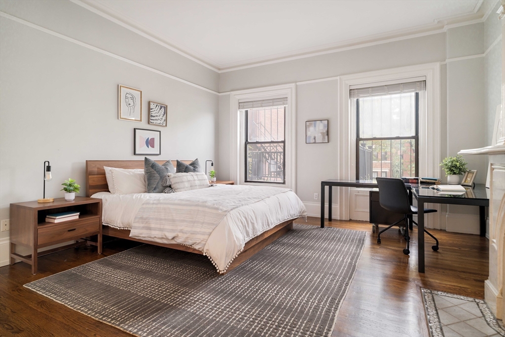 530 Massachusetts Avenue, Unit 2 Boston, MA 02118 - Photo 15 of 33 a bedroom with a bed a table and chair with wooden floor
