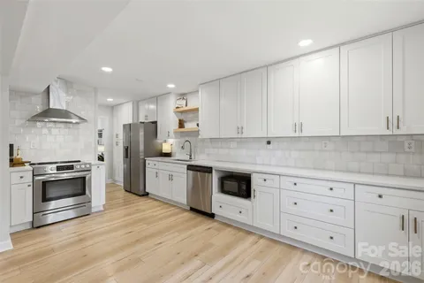 a kitchen with granite countertop white cabinets stainless steel appliances and wooden floor