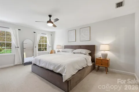 a large bed sitting in a bedroom next to a window and a chandelier