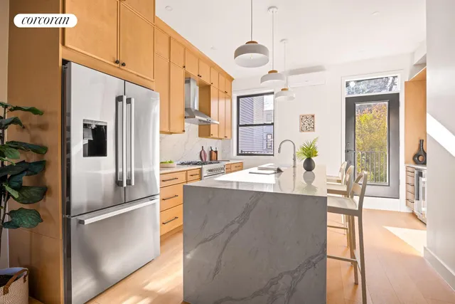 a kitchen with stainless steel appliances granite countertop a refrigerator a oven a sink and a dining table with wooden floor