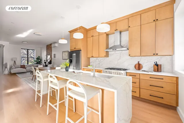 a kitchen with stainless steel appliances kitchen island granite countertop a stove a sink and white cabinets with wooden floor