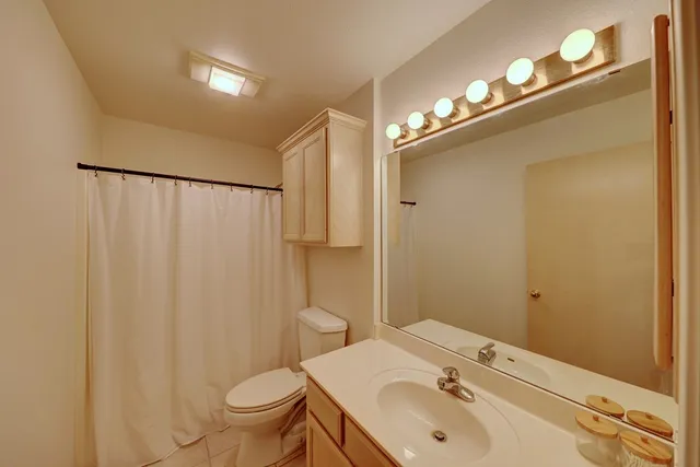 a bathroom with a sink a toilet a mirror and shower