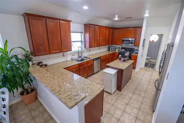 a large kitchen with kitchen island granite countertop a sink a counter top space and cabinets