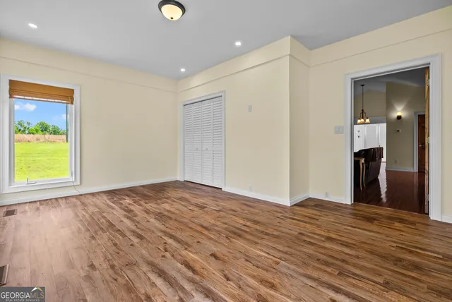 a view of an empty room with wooden floor and a window