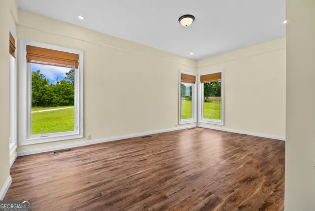an empty room with wooden floor and windows
