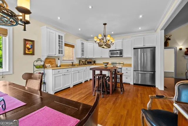 a kitchen with stainless steel appliances a dining table chairs stove and refrigerator