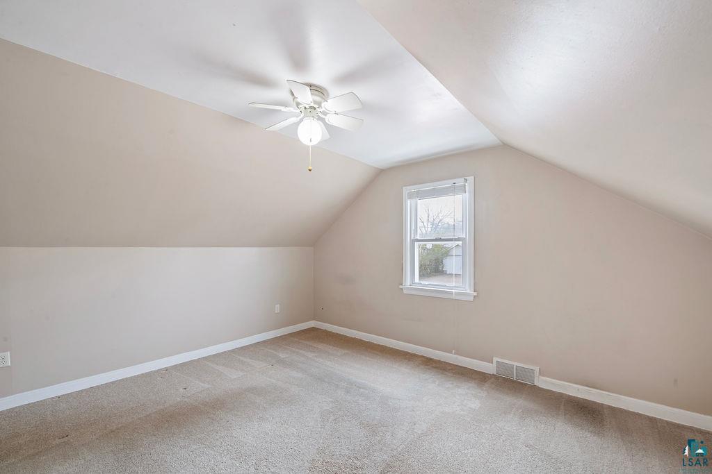 122 3rd Street Cloquet, MN 55720 - Photo 10 of 42 Carpeted room featuring sloped ceilings, a ceiling fan with light fixture, and a single pane window with white trim