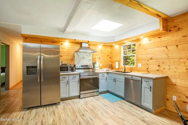 a kitchen with stainless steel appliances granite countertop a refrigerator a sink dishwasher a stove with wooden cabinets and floor