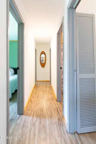 a view of a hallway with wooden floor and a bathroom