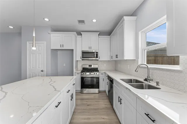 a kitchen with granite countertop a sink stove and refrigerator