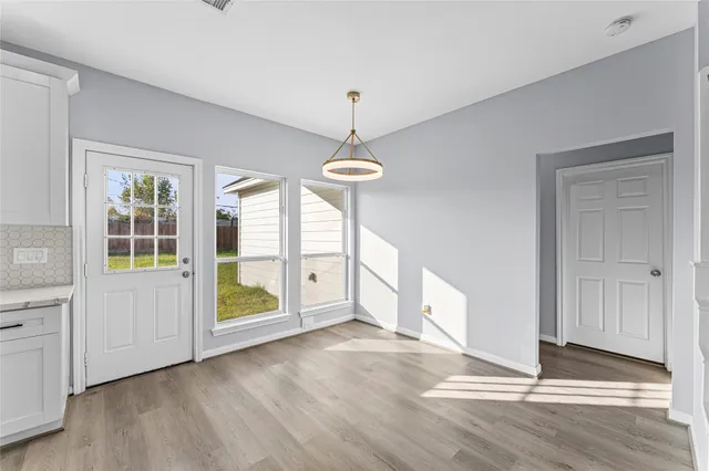 a view of an empty room with a window and wooden floor