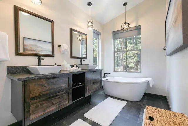 a spacious bathroom with double vanity a bathtub mirror and a sink