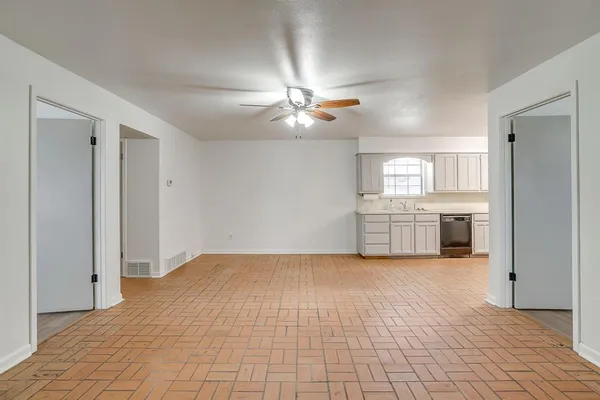 a view of an empty room and chandelier fan