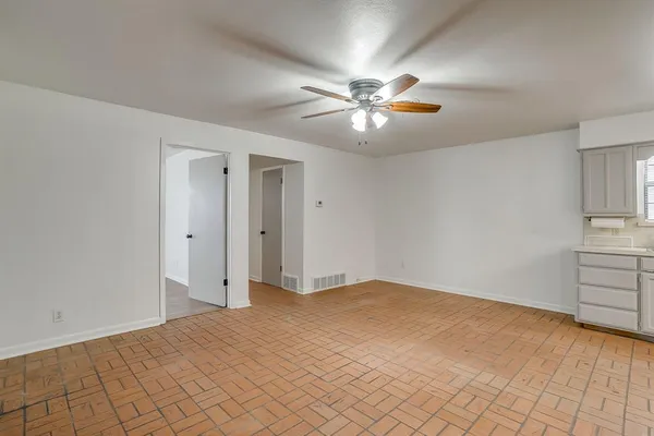 a view of an empty room with chandelier fan