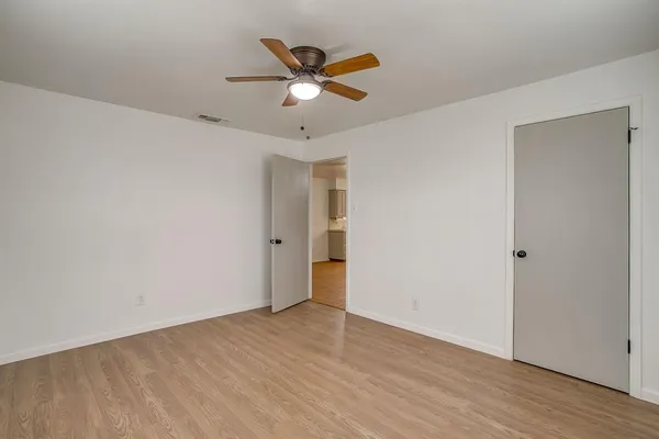 an empty room with wooden floor fan and windows