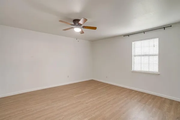 an empty room with wooden floor fan and windows
