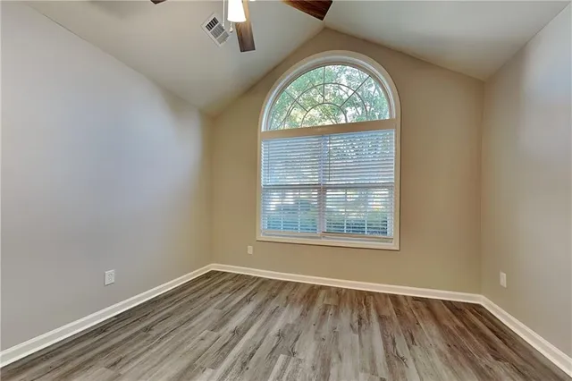 an empty room with wooden floor chandelier and windows