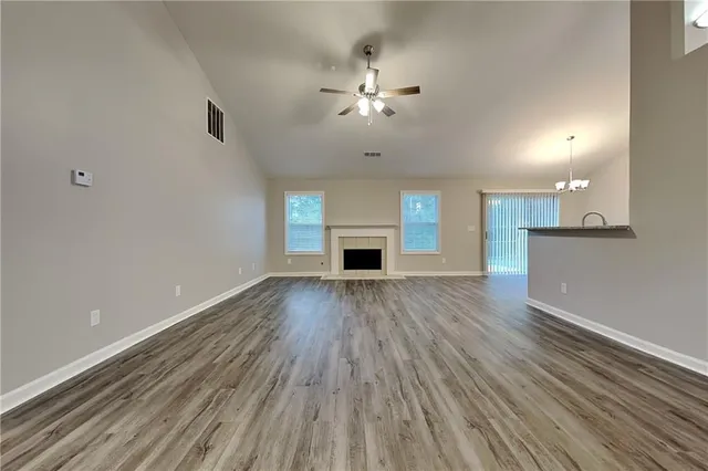 an empty room with wooden floor fireplace and windows