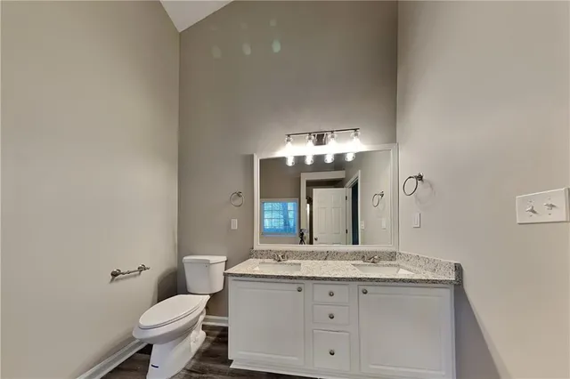 a bathroom with a granite countertop toilet a sink and a mirror
