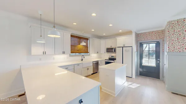 a large white kitchen with lots of counter space and refrigerator