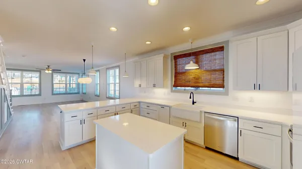 a large white kitchen with a large window a sink and appliances