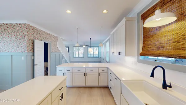 a large white kitchen with a sink a refrigerator and window