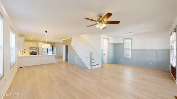 a view of a hallway with wooden floor and a ceiling fan
