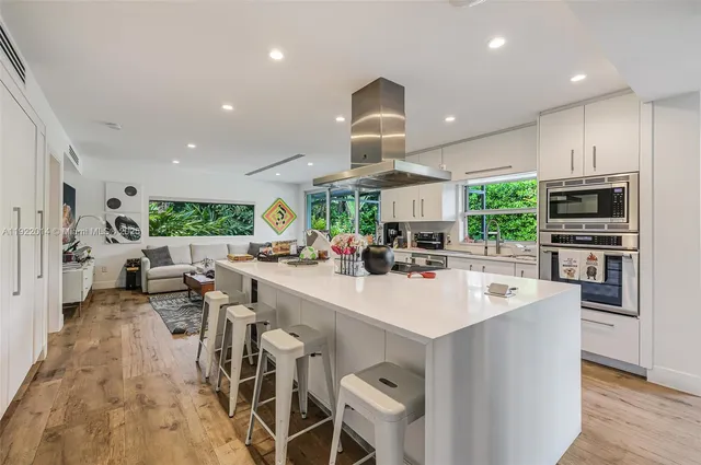 a kitchen with stainless steel appliances a sink a stove a refrigerator cabinets and living room view