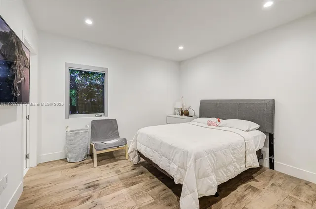 a bedroom with a bed a chair and painting on the wall