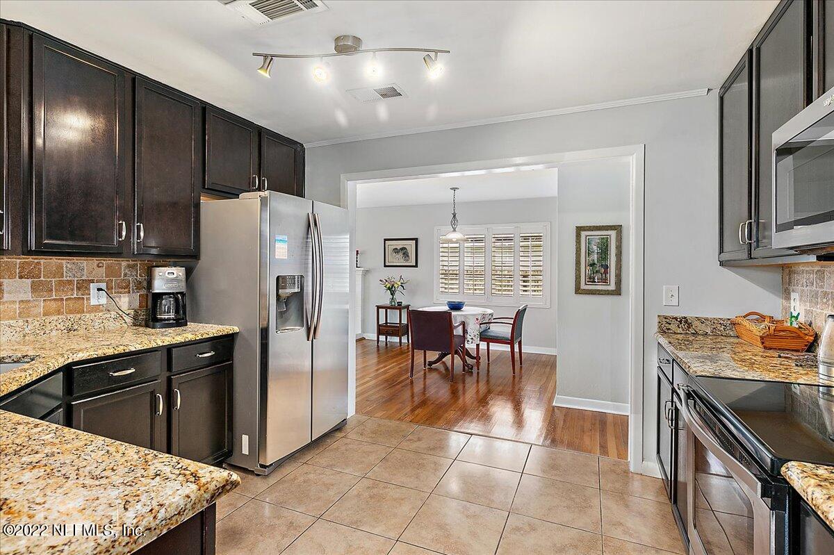 6136 Duke Road Jacksonville, FL 32217 - Photo 6 of 23 a kitchen with stainless steel appliances kitchen island granite countertop a refrigerator a stove a sink a dining table and chairs