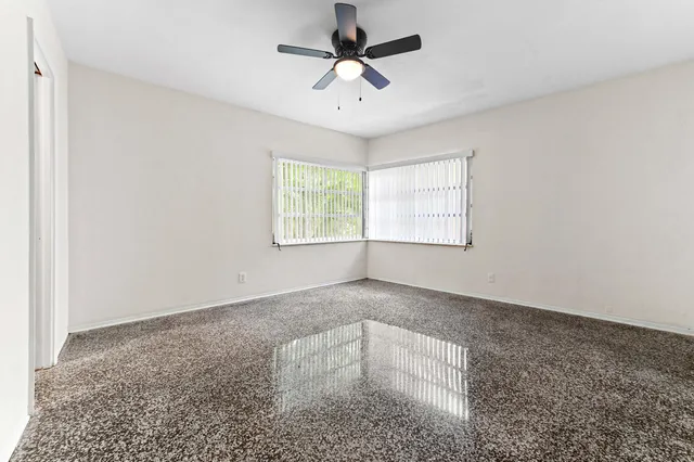 an empty room with windows and ceiling fan
