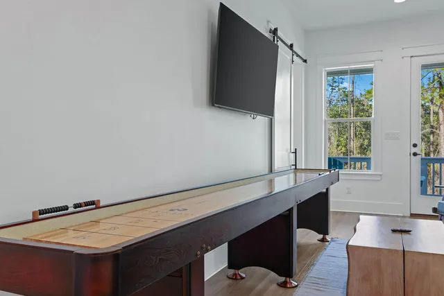 a bedroom with a bed a table and chair with wooden floor