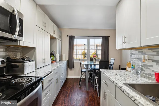a kitchen with granite countertop a stove top oven a sink a dining table and chairs