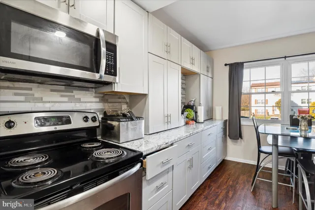a kitchen with a stove a sink and wooden floor